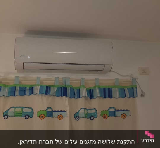 מזגן מותקן על קיר מעל וילון צבעוני